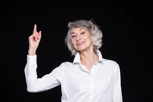 Porträt einer modernen, glücklichen Seniorin, die nach oben zeigt, isoliert auf schwarzem Hintergrund — Stockfoto