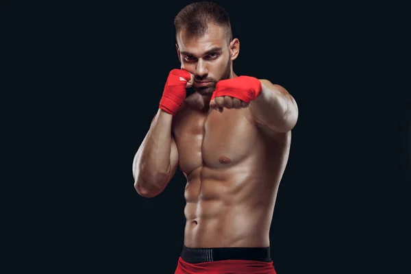 Fechar uo vista frontal de um homem desportivo em luvas de boxe praticando técnicas de luta isoladas em fundo preto — Fotografia de Stock