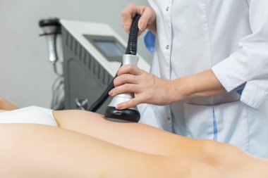 İnce bir kadın, ultrason etkisiyle yağ hücrelerini ayırmak için güzellik salonunda sıkı kalçalarına anti-selülit ve anti-yağ terapisi uygular.