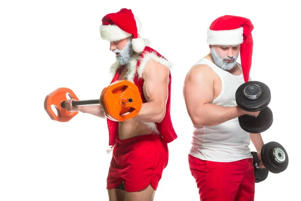 Natale. Ritratto di due forti atleti muscolosi barbuti in costume da Babbo Natale, allenamento sollevando bilancieri isolati su sfondo bianco — Foto Stock