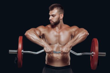 Siyah arka planda izole edilmiş halteri kaldıran güçlü bir vücut geliştiricinin ön görüntüsü.