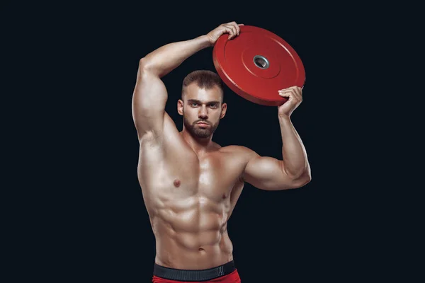Retrato de sexy muscular masculino com um disco de barra levantada acima de sua cabeça isolada em fundo preto — Fotografia de Stock