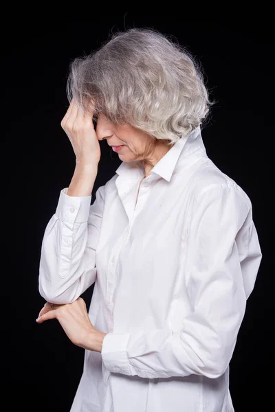 Porträt einer alten, aber modernen trendigen Frau, die unter Kopfschmerzen oder Migräne leidet und ihren Kopf in den Händen hält, mit verzweifeltem Gesichtsausdruck, isoliert auf schwarzem Hintergrund — Stockfoto