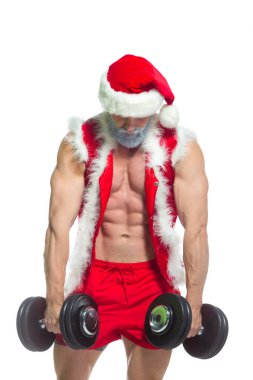 Noel zamanı. Kaslı, gri sakallı, Noel şapkalı ve kırmızı şortlu Noel Baba spor salonunda ağır bir halteri kaldırıp beyaz arka planda izole edilmiş bir egzersiz yapıyor..