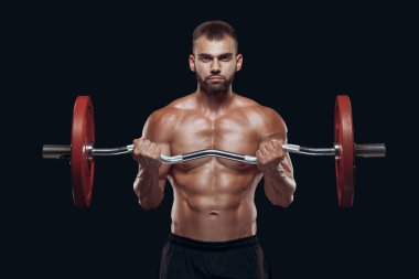 Siyah arka planda izole edilmiş halterle egzersiz yapan güçlü bir vücut geliştiricinin ön görüntüsü.