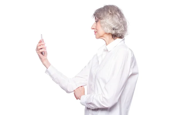 Mulher de cabelos grisalhos madura bonita está sorrindo usando um smartphone assistindo vídeo ou conversando isolado no fundo branco — Fotografia de Stock