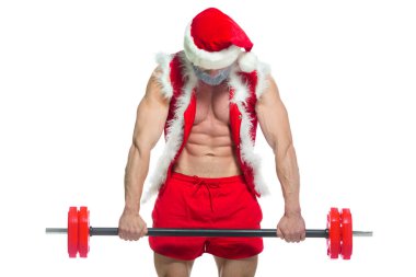 Noel zamanı. Gri sakallı, Noel şapkalı ve kırmızı şortlu güçlü kaslı Noel Baba spor salonunda ağır bir halteri kaldırıp beyaz arka planda izole edilmiş bir egzersiz yapıyor..