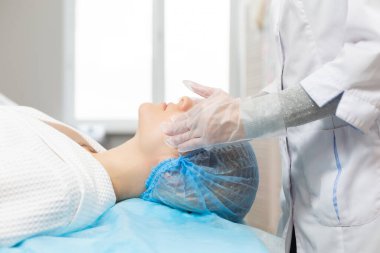 Güzellik salonunda yüz masajı sırasında kanepede dinlenen bir kızın yan görüntüsü. Yüz derisinin nemlendirici ve yenilenmesi