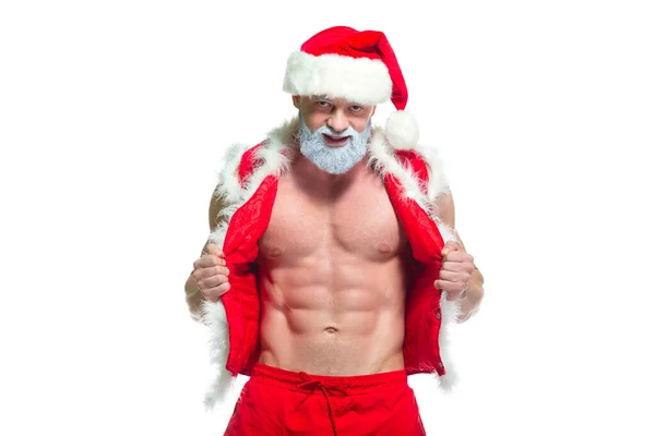 Julen. Porträtt av muskulös sexig stark idrottsman i Santa Claus kostym med grått skägg poserar visar hans abs isolerad på vit bakgrund — Stockfoto