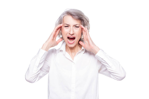 Studio shot of distressed irritated senior woman losing temper screaming out loud from pain and holding hands on head troubled and concerned being pissed and fed up, isolated on white background