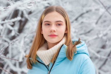 Düşünceli bir kızın portresi. Kış karlı parkta donmuş ağaçlara karşı duruyor. Yılbaşında.