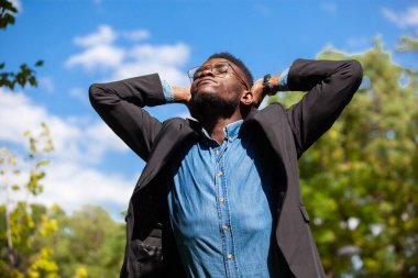 Özgürlük için. Genç siyahi bir ofis çalışanı, bir yaz parkında teneffüs yapıyor.