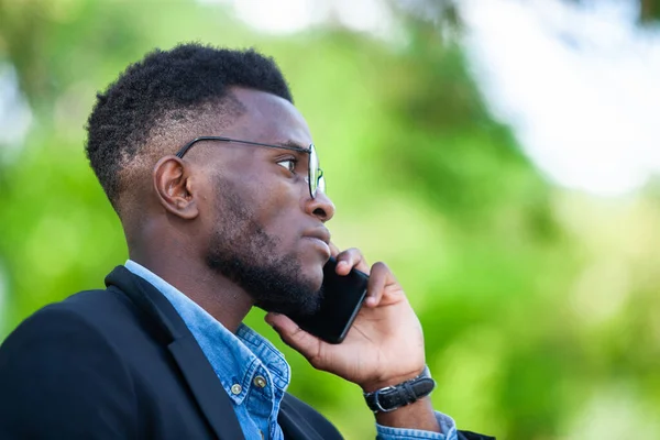 Genç Afrikalı girişimci iş konularına odaklanıyor ve parktaki iş anlaşmaları için cep telefonuyla iletişim kuruyor — Stok fotoğraf