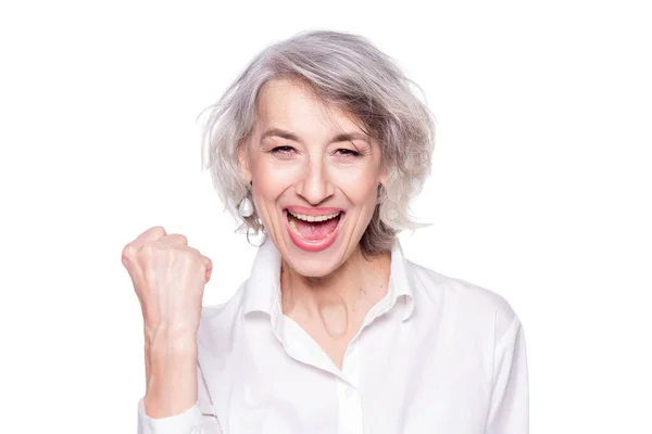 Porträt einer fröhlichen, fröhlichen Seniorin, die laut schreit und den Sieg mit erhobener Faust vor weißem Hintergrund gestikuliert — Stockfoto