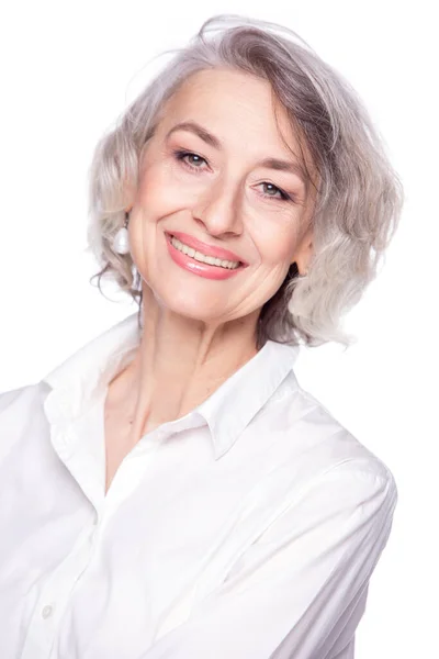 Close-up portret van aangename grijs-harige vrouw van middelbare leeftijd kijken naar de camera met een brede glimlach en tonen geluk, geïsoleerd op witte studio achtergrond — Stockfoto