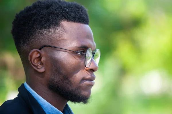 Крупный план портрета уверенного африканского бизнесмена в очках, гуляющего в летнем парке — стоковое фото
