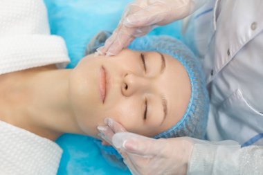 Güzellik salonunda yüz masajı sırasında kanepede dinlenen bir kızın yan görüntüsü. Yüz derisinin nemlendirici ve yenilenmesi