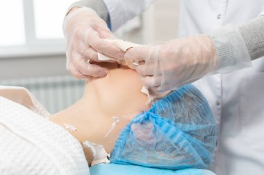 Güzellik salonunda bir kozmetik uzmanı tarafından aljinat maskesinin çıkarılması. Deriyi temizler ve nemlendirir, şişkinliği kaldırır ve kaldırır