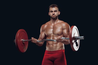 Siyah arka planda izole edilmiş halteri kaldıran güçlü bir vücut geliştiricinin ön görüntüsü.