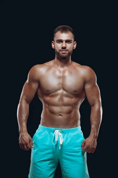 Muskularne i dopasowanie młody kulturysta fitness mężczyzna model pozowanie na odizolowanym czarnym tle — Zdjęcie stockowe