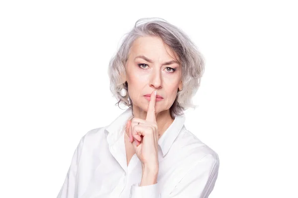 Середнього віку красива жінка прикладає палець до губ з замороженим і суворим виглядом, просячи тихого, ізольованого на білому тлі — стокове фото