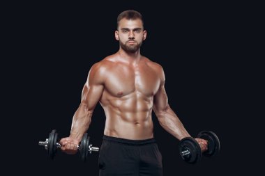 Seksi atletik erkek, siyah arka planda izole bir şekilde başı aşağıda duran, kaslı ve halterli bir vücut gösteriyor.