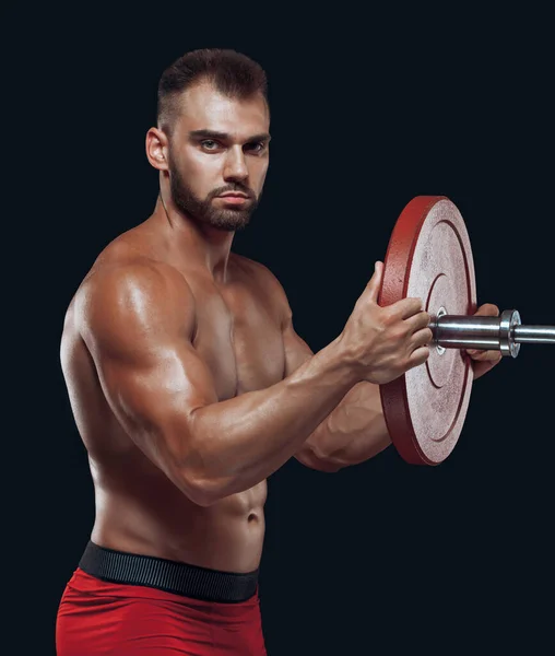 Vista lateral de un atleta masculino colocando un disco sobre una barra aislada sobre fondo negro — Foto de Stock