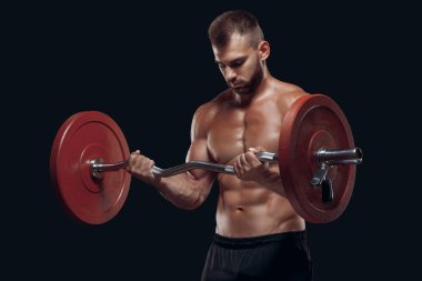 Siyah arka planda izole edilmiş halterle egzersiz yapan güçlü bir vücut geliştiricinin ön görüntüsü.