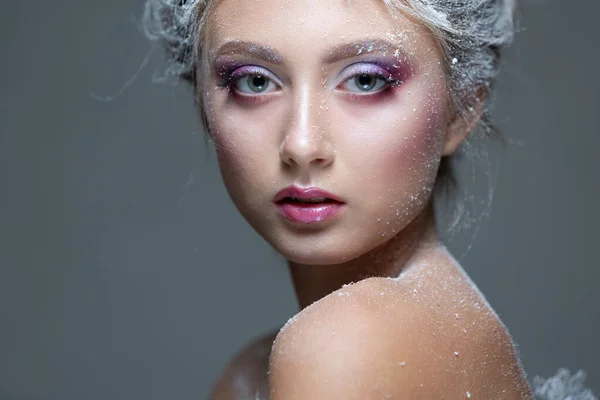 Winter Beauty Woman in clothes made of frozen flowers covered with frost, with snow on her face and shoulders. Christmas Girl Makeup. Make-up the snow Queen. Isolated on a gray background. Close-up. — Stock Photo, Image