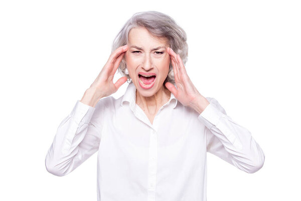 Studio shot of distressed irritated senior woman losing temper screaming out loud from pain and holding hands on head troubled and concerned being pissed and fed up, isolated on white background