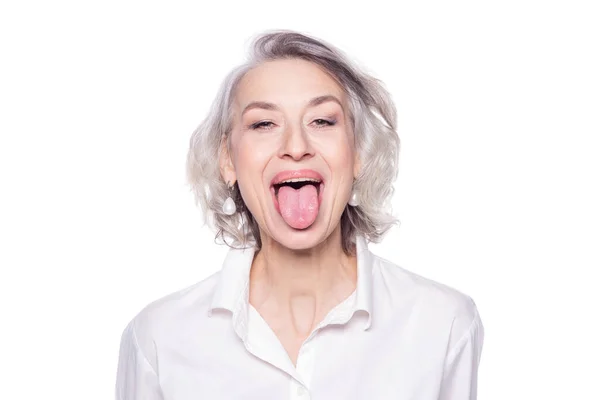 Skott av en vacker mogen kvinna som har roligt och retas sticker ut tungan isolerad på vit bakgrund — Stockfoto