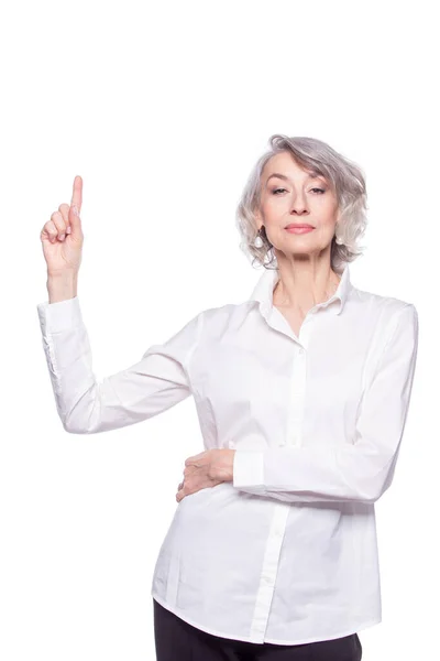 Ritratto di una donna anziana moderna che punta verso l'alto e guarda la macchina fotografica con espressione seria, isolata su sfondo bianco — Foto Stock