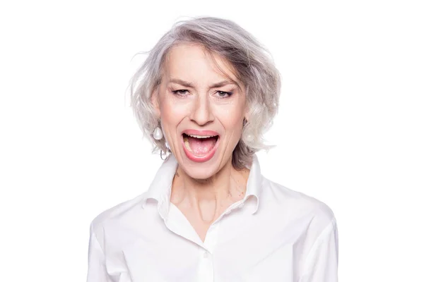 Foto av mogen vacker gråhårig kvinna som skriker och skriker högt med en vidöppen mun med ett argt uttryck isolerat på vit bakgrund — Stockfoto