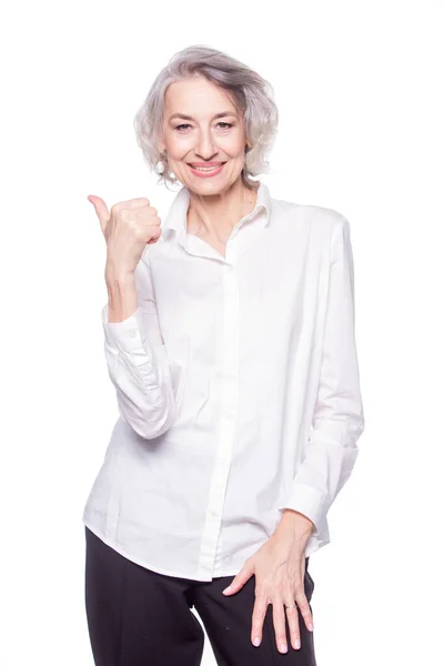 Portrait of a happy smiling mature woman in her sixties with trendy grey hair making thumbs up hand sign expressing approval isolated on white background — Stockfoto