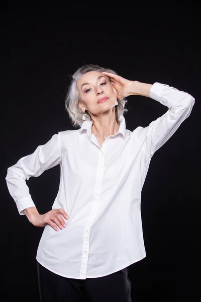 Una imagen de una mujer adulta madura y segura de sí misma de pelo gris aislada sobre un fondo negro —  Fotos de Stock