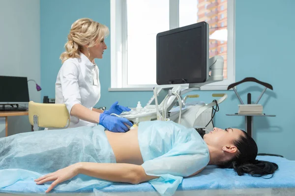 Fotografie eines Arztes, der eine Ultraschallsonde auf dem Bauch einer schwangeren Frau während eines geplanten Termins bewegt — Stockfoto