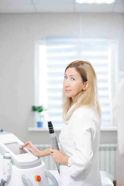 Schöne Ärztin steht in einem modern ausgestatteten Schönheitssalon und hält ein Kohlenstoff-Peeling-Werkzeug in der Hand — Stockfoto