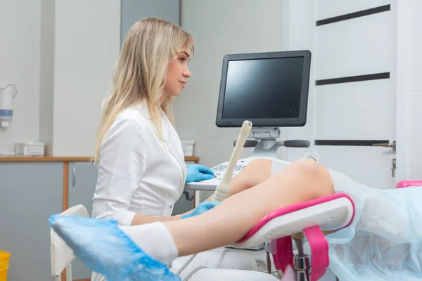 Ein Gynäkologe führt eine Ultraschalldiagnostik für ein Mädchen durch, das auf einem gynäkologischen Stuhl liegt. Schwangerschaftsmanagement, Überwachung der Gesundheit des Fötus — Stockfoto