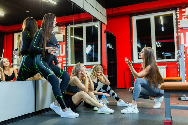 Cztery zmęczone, szczęśliwe atletyczne dziewczyny rozmawiają i relaksują się po ciężkim treningu na siłowni — Zdjęcie stockowe
