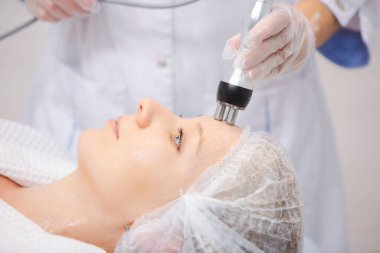 Modern bir güzellik salonunda RF kaldırma işlemi sırasında rahatlayan güzel bir kadının portresini yakından çek.