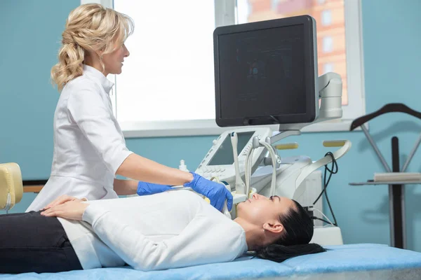 Paciente feminina está deitada em um sofá durante o procedimento de diagnóstico ultrassonográfico da glândula tireóide. Prevenção do hipertiroidismo — Fotografia de Stock