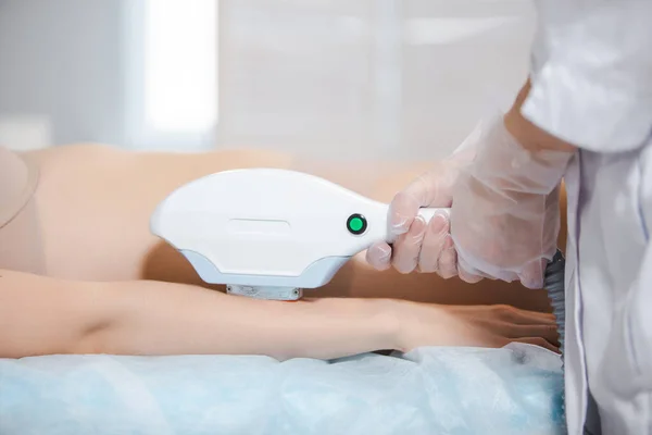 Närbild laser hårborttagning på armen på en ung flicka av en professionell specialist i en modern kosmetologi kontor — Stockfoto