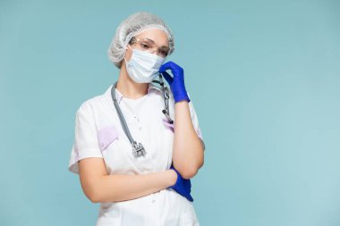 Üzüntü, üzüntü, yorgunluk. Mavi arka planda steteskoplu, koruyucu kıyafetli bir doktor ya da hemşire. Maskeli, eldivenli, gözlüklü ve şapkalı. Kopyala yapıştır. sağlık hizmeti kavramı.