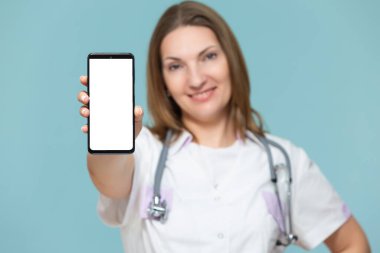 Mavi arka planda akıllı telefonu olan bir kadın doktor. Reklam için yer var. Kopyala yapıştır. sağlık hizmeti kavramı.