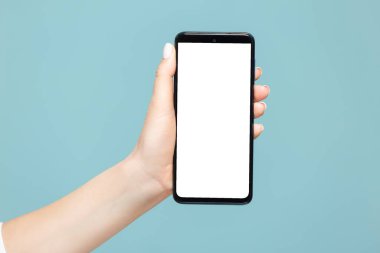 Mavi arka planda beyaz bir reklam ekranı olan akıllı telefonlu bir kadın elinin yakın çekimi. Yapıştırıcı kopyala.