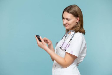 Akıllı telefonlu bir kadın doktor, mavi arka planda hastaya telefonla destek veren çevrimiçi bir konsültasyon yapıyor. Kopyala yapıştır. Uzaklık sağlık hizmeti kavramı.