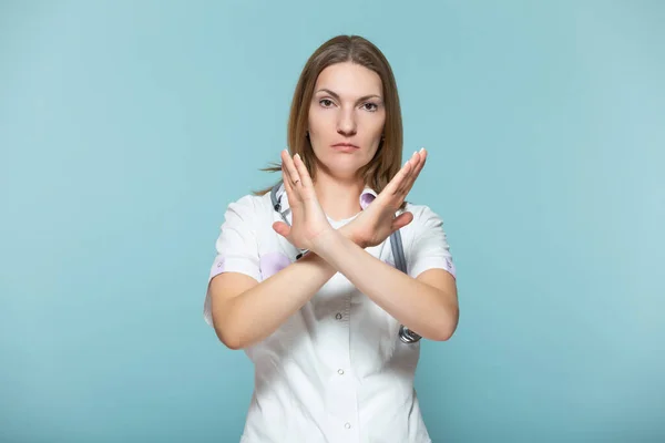 Bella dottoressa con uno stetoscopio, mostra un segno di stop con la mano, su uno sfondo blu. Copia incolla. concetto di assistenza sanitaria. Fermiamo la malattia. — Foto Stock