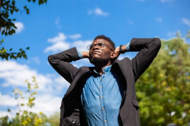 Özgürlük için. Genç siyahi bir ofis çalışanı, bir yaz parkında teneffüs yapıyor.