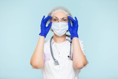 Mavi arka planda steteskoplu, koruyucu kıyafetli bir doktor ya da hemşire. Maskeli, eldivenli, gözlüklü ve şapkalı. Kopyala yapıştır. sağlık hizmeti kavramı.