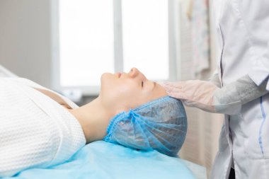 Güzellik salonunda yüz masajı sırasında kanepede dinlenen bir kızın yan görüntüsü. Yüz derisinin nemlendirici ve yenilenmesi